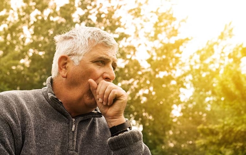man covering his mouth outside